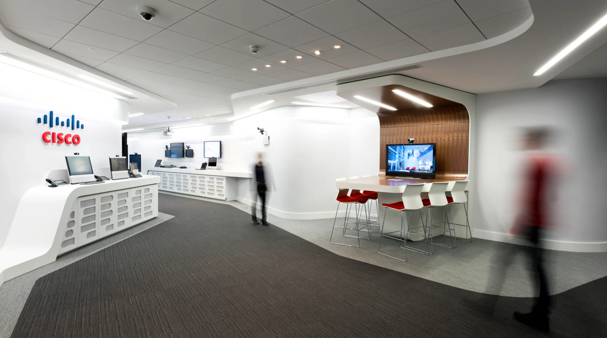 cisco reception with logo on the wall, people walking through and brown glossy booth seating