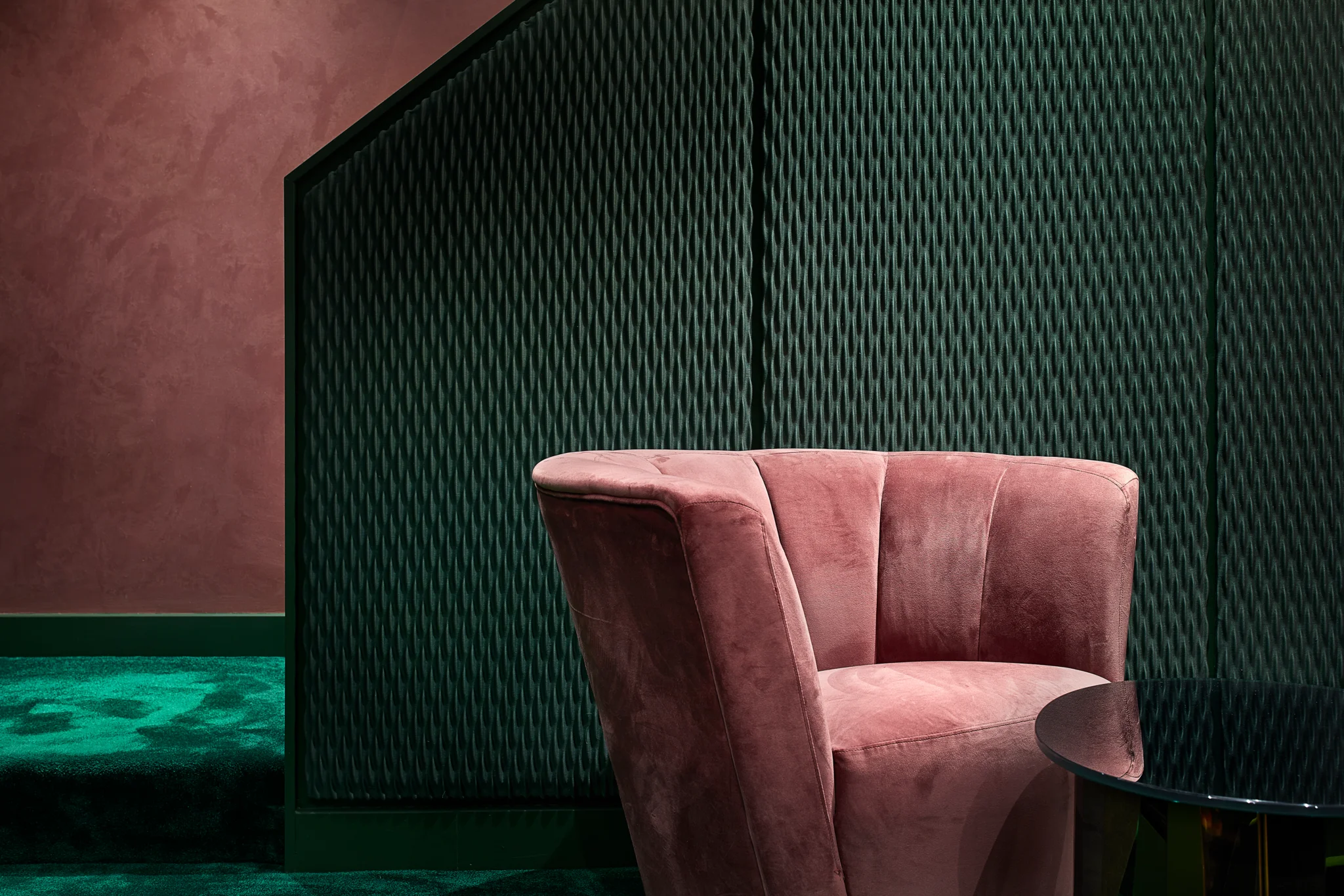 pink velvet chair against a green textured wall