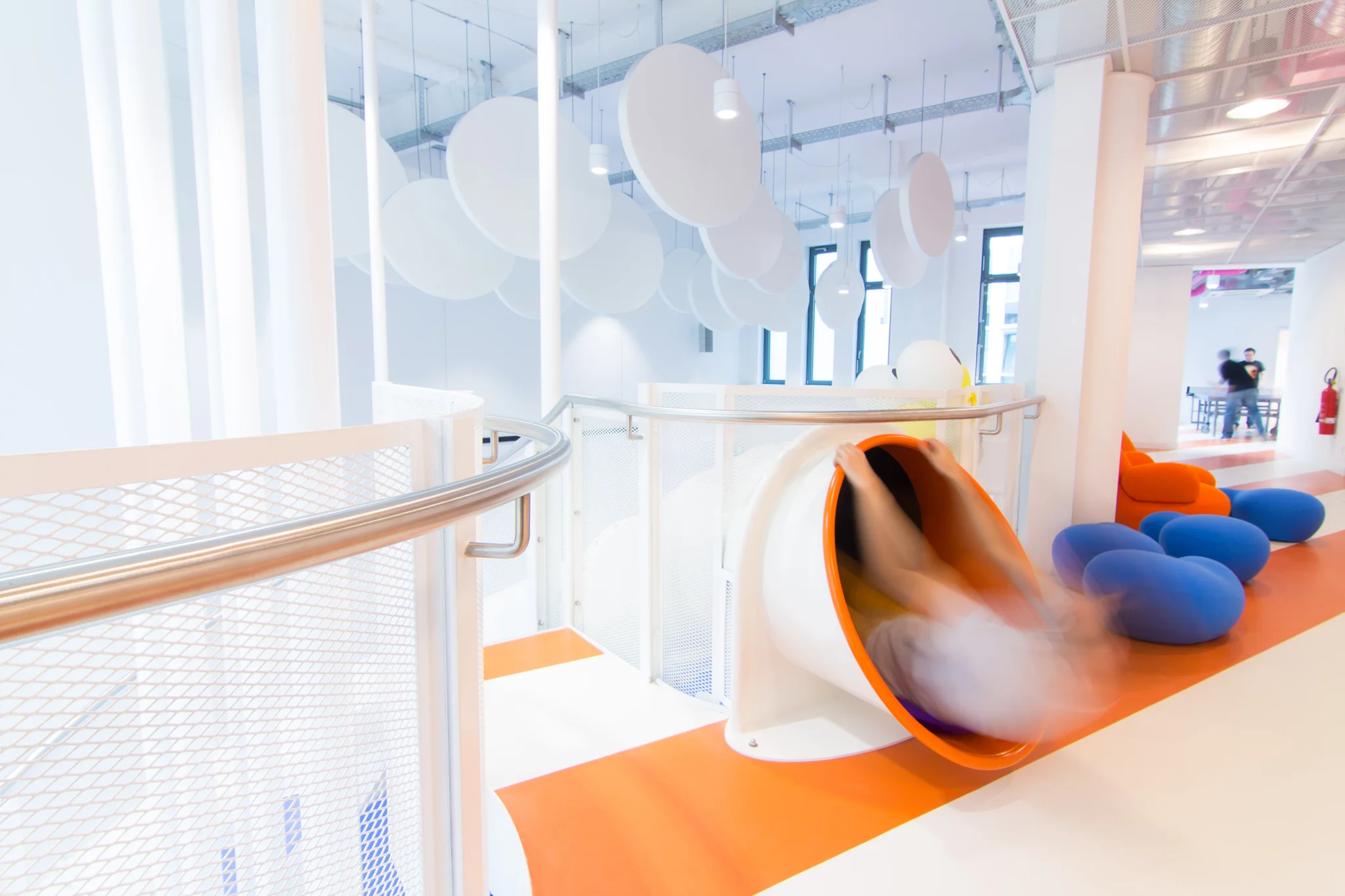 orange and white striped floor with a man going down a slide/flume