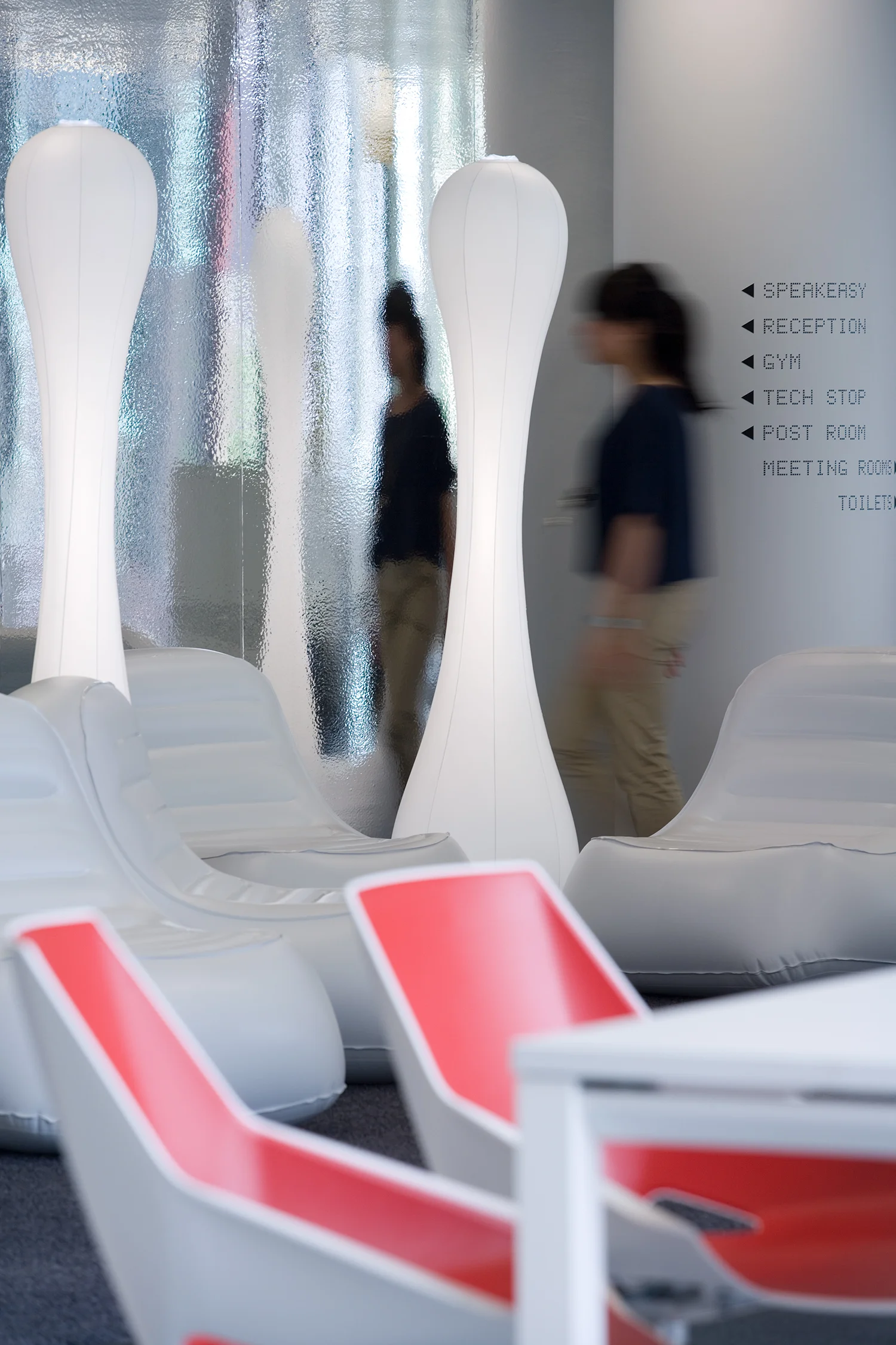 person walking away from inflatable chairs and lights, with red chairs in the foreground