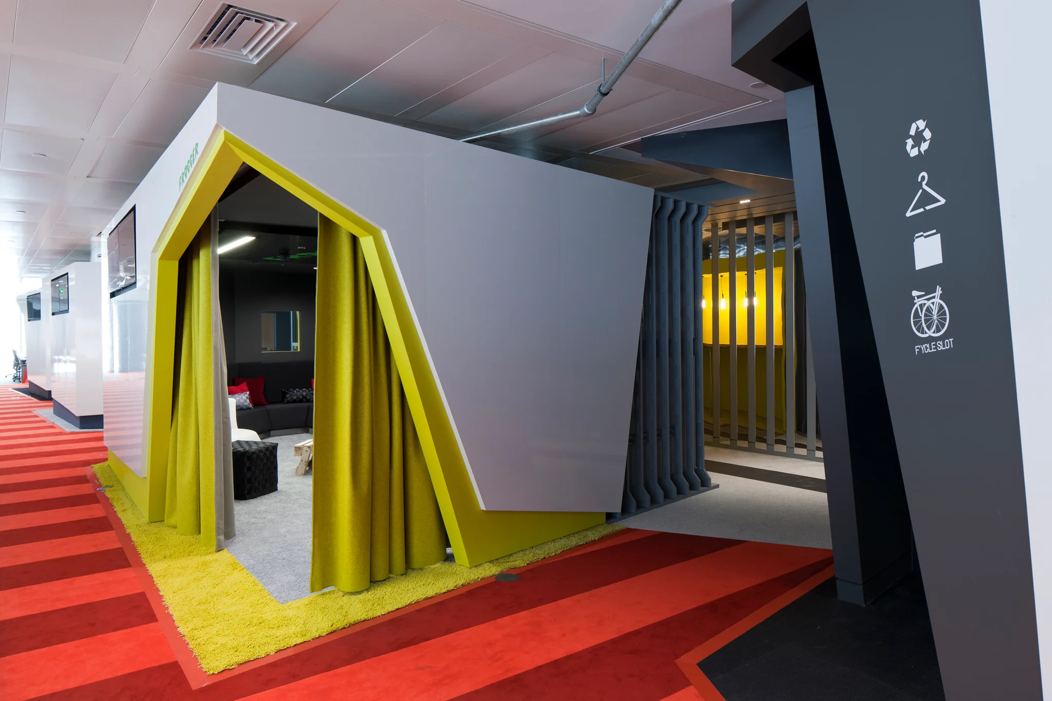 A red carpeted area with a white and green pod that opens into a work space