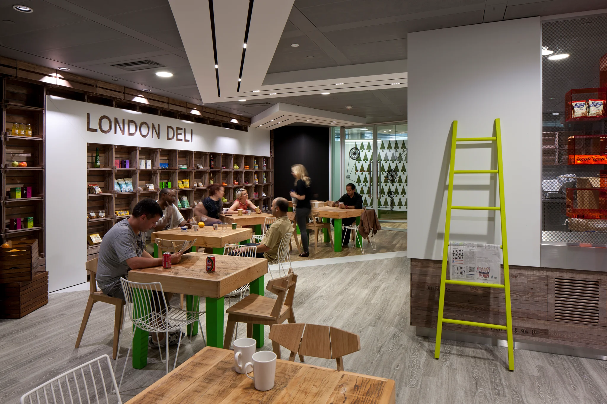 Google kitchen with eclectic wooden furniture, 'London Deli' written on the wall with food products underneath