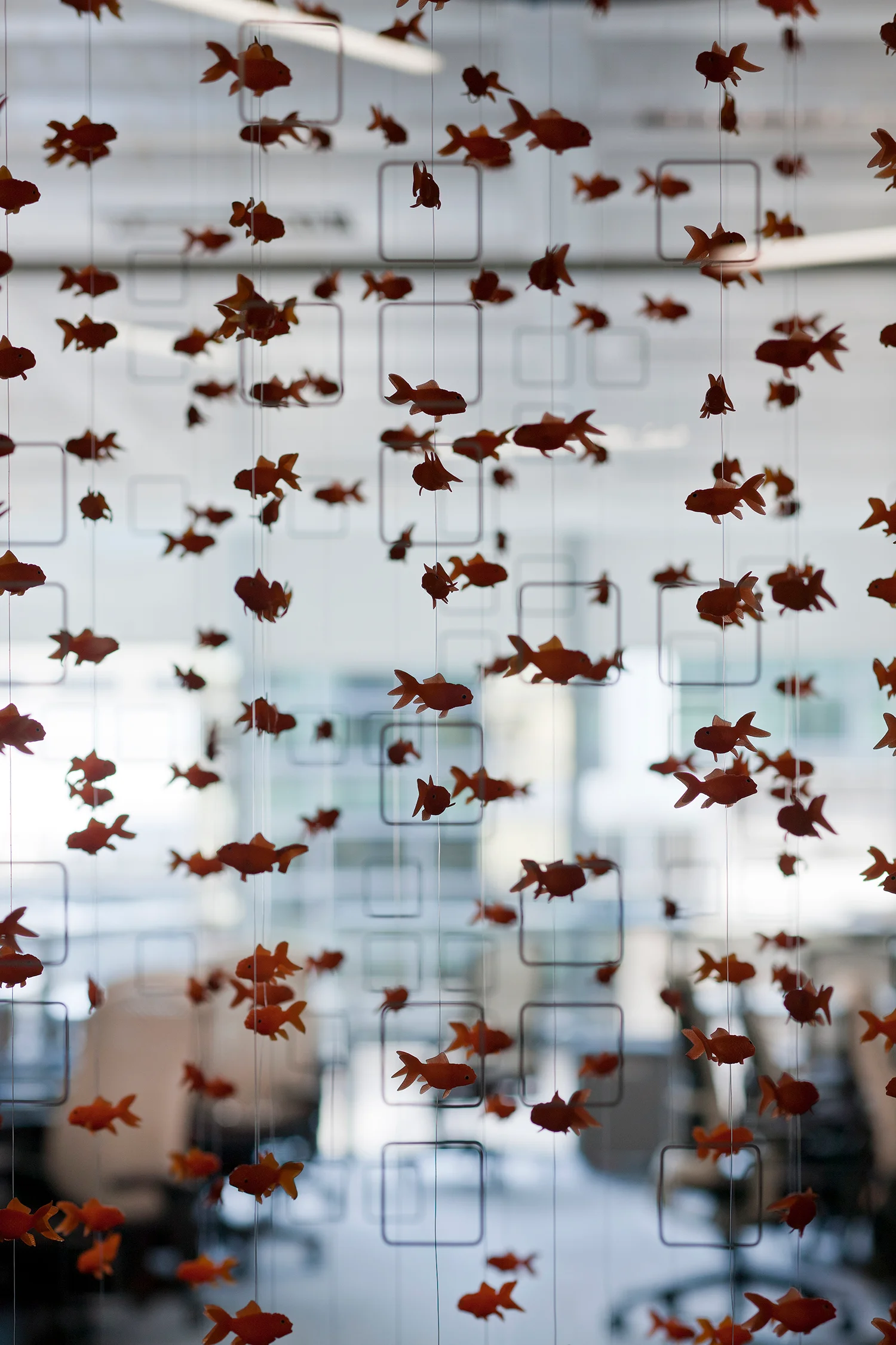 multiple plastic goldfish hanging in front of a glass window