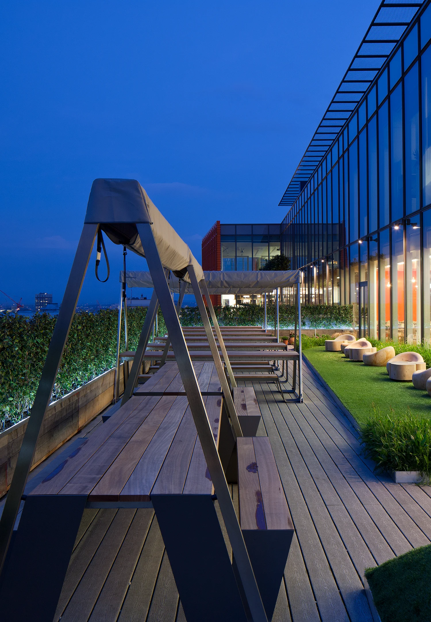 outdoor terrace with bench seating and hedges overlooking London at night