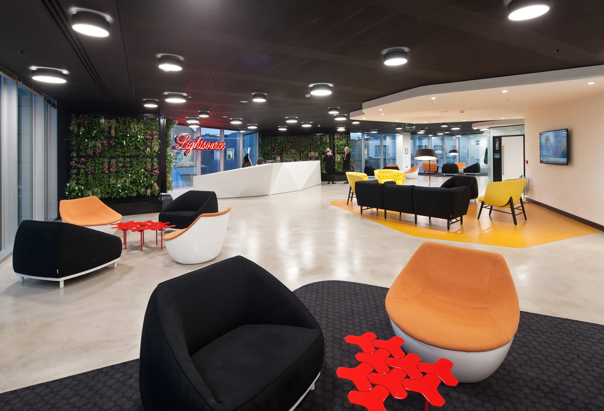 reception area with bright orange sofa, looking towards the main reception and living walls