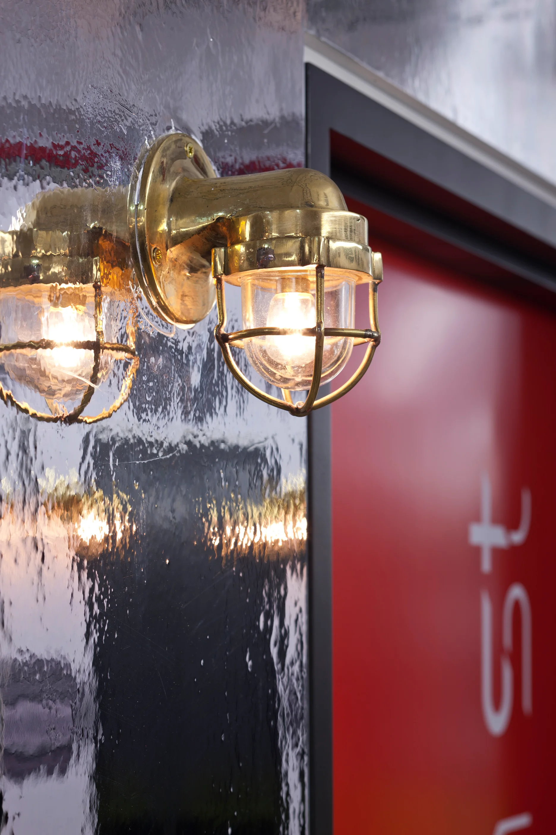 a vintage style cargo-ship gold wall light against a glossy background wall
