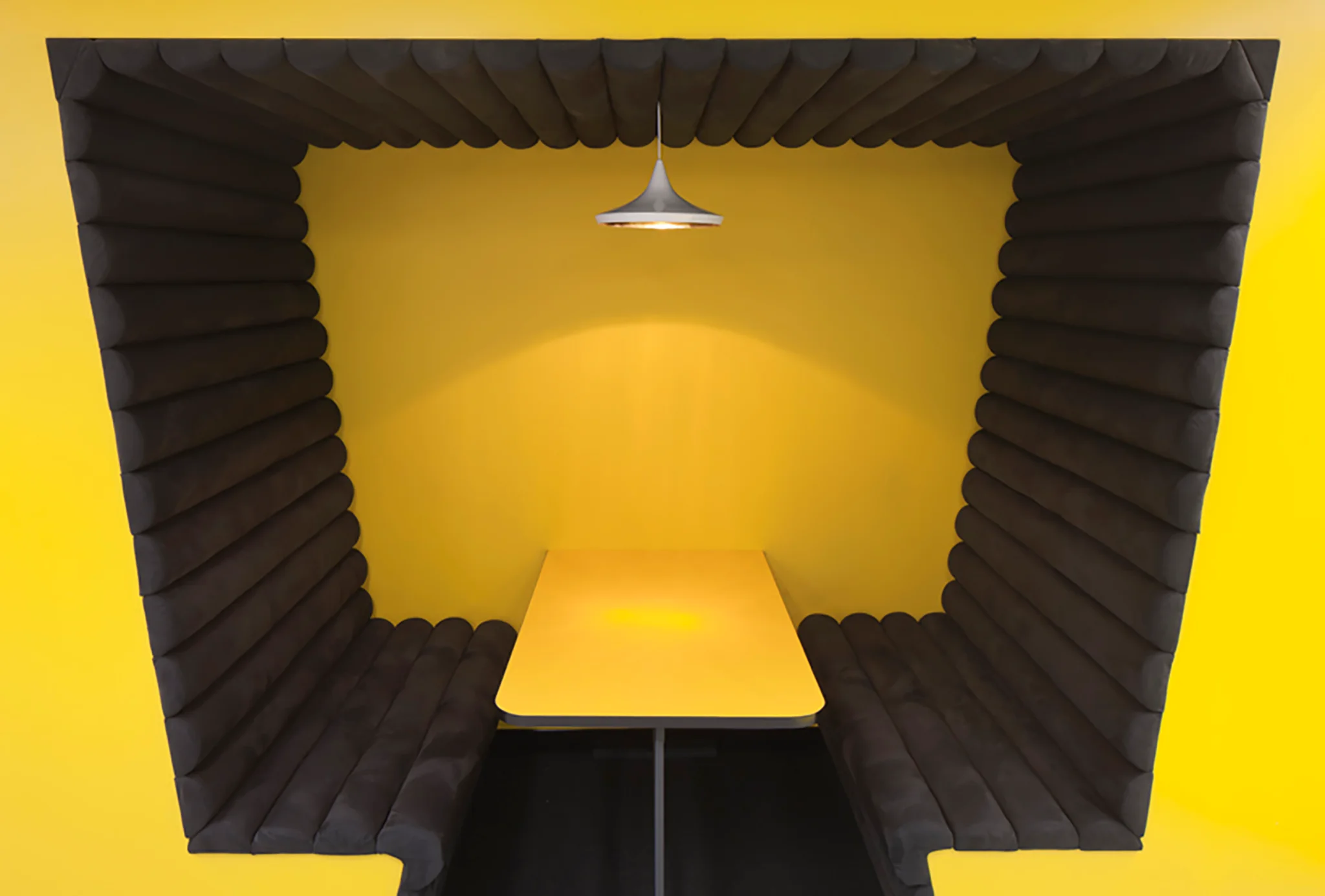 a bright yellow booth with black seating and a yellow table inside