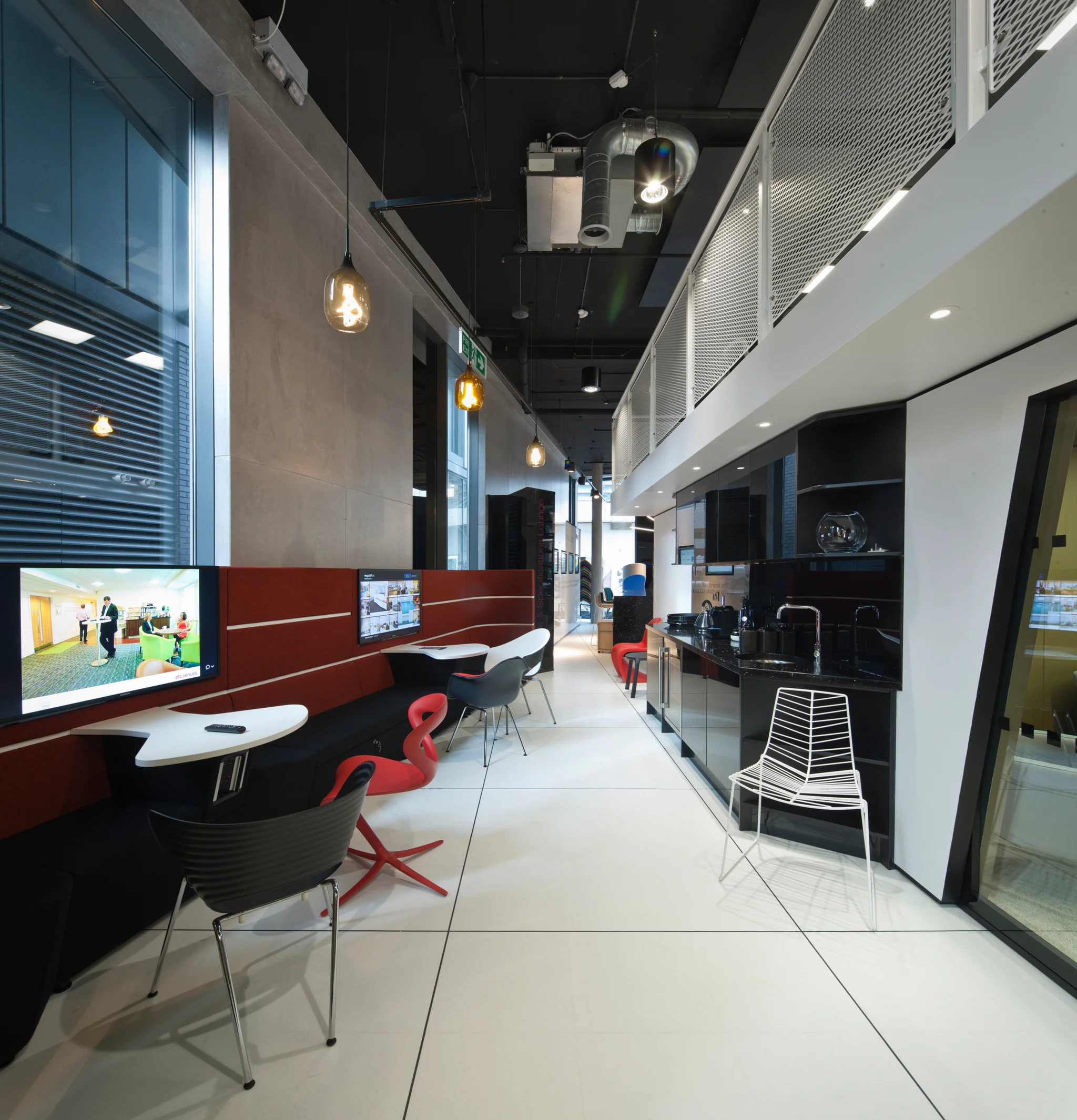 a range of modern furniture within a modern designed long corridor-like space, with desks and counter tops running down the left hand side