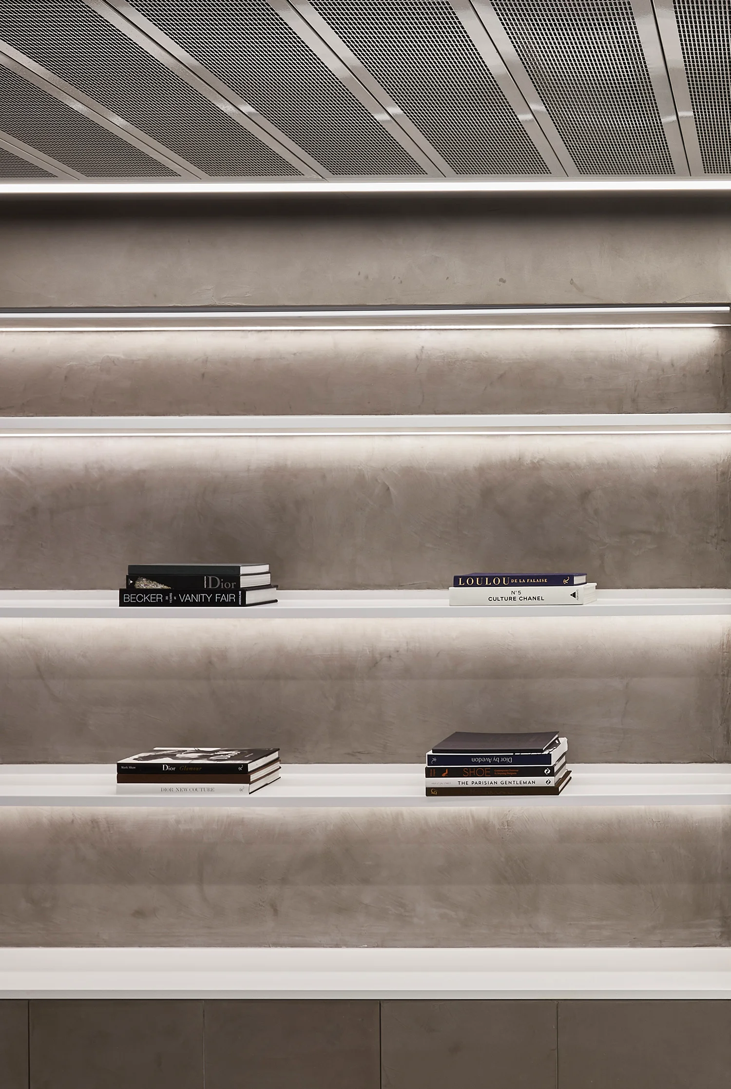 Concrete lit shelving with a range of fashion house books stacked together