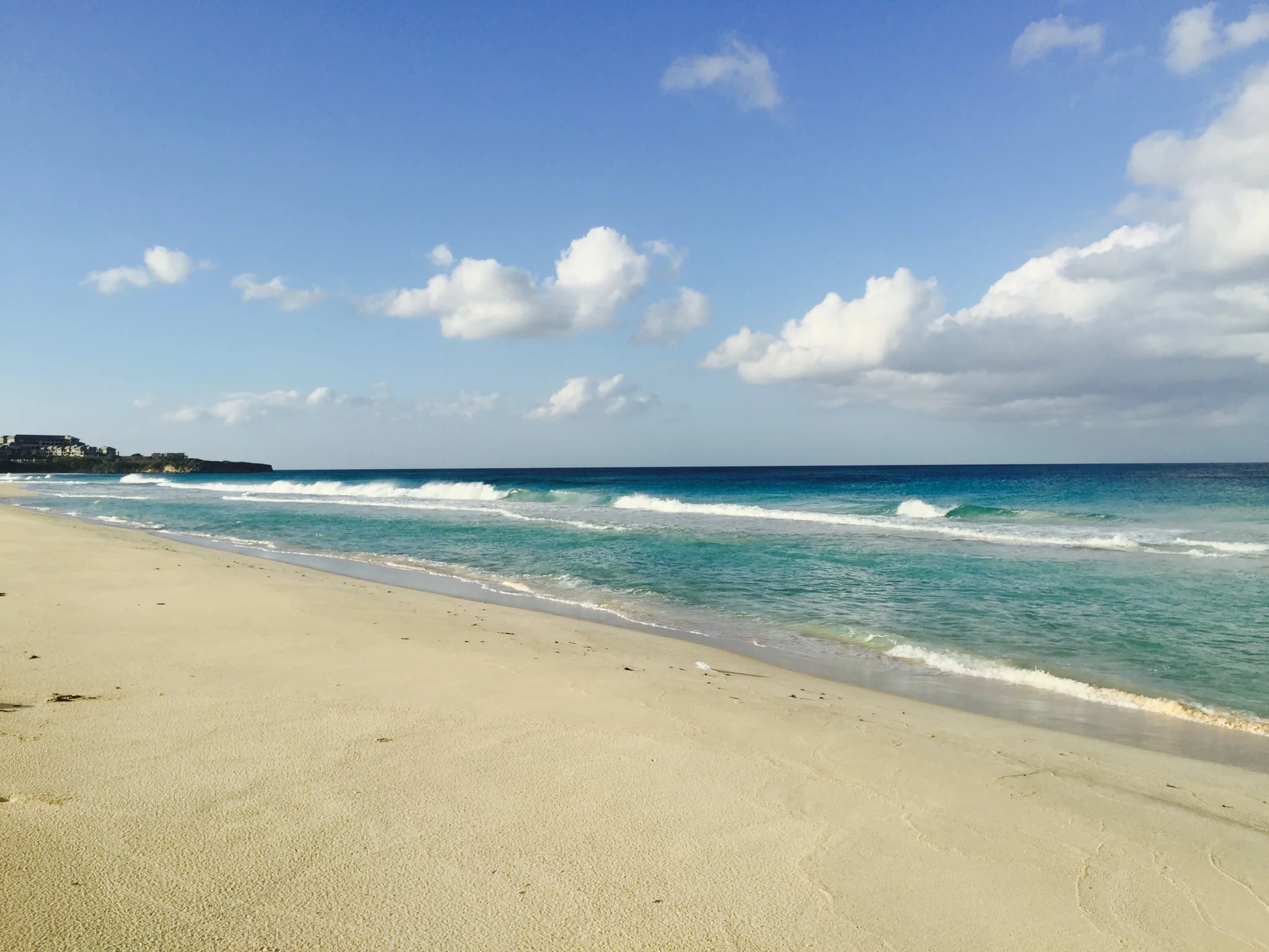 A front on image of sunny white sandy beach with the sea and waves