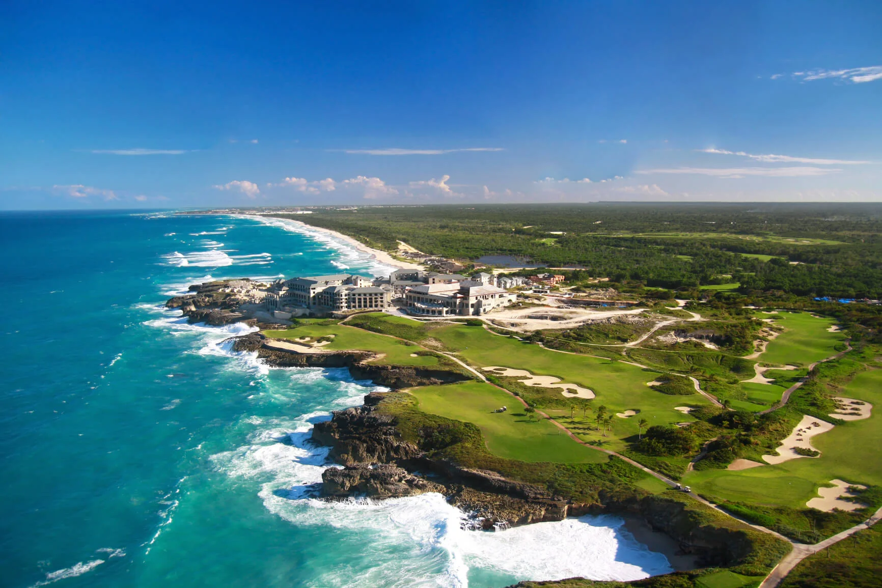 Aerial image of the Roco-Ki resort set against bright blue sea and sky and the rest of the green land