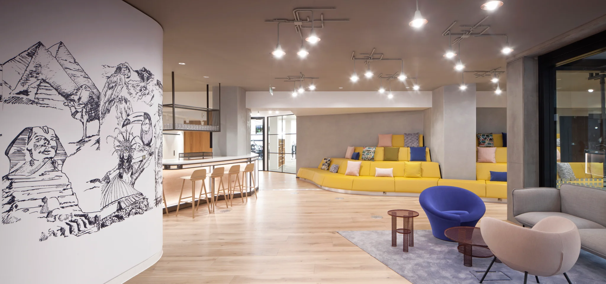 欢迎区有木质地板，紫色椅子和休息区，有黄色的分层座椅和坐垫。左边的木制和大理石茶点