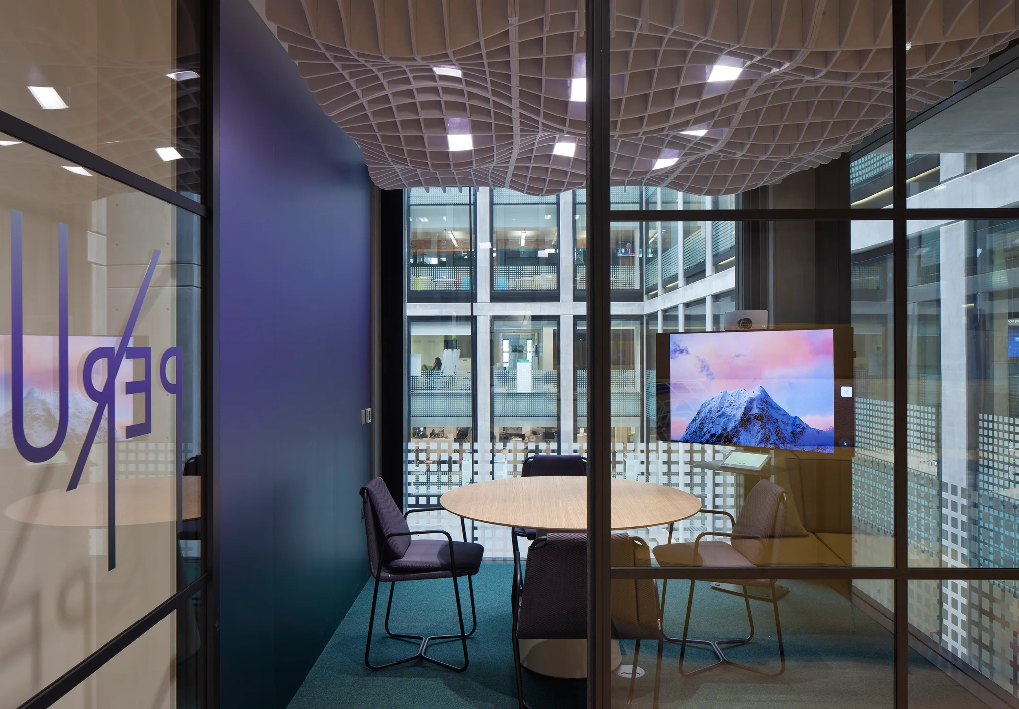 紫色的会议室，玻璃上有 "puru "的名字。浅紫色的波状声学天花板悬挂在桌子和椅子上方